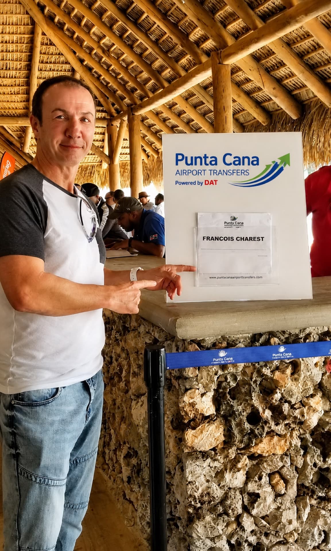 Um viajante no ponto de encontro da Punta Cana Airport Transfers ao lado de uma placa com o nome do passageiro